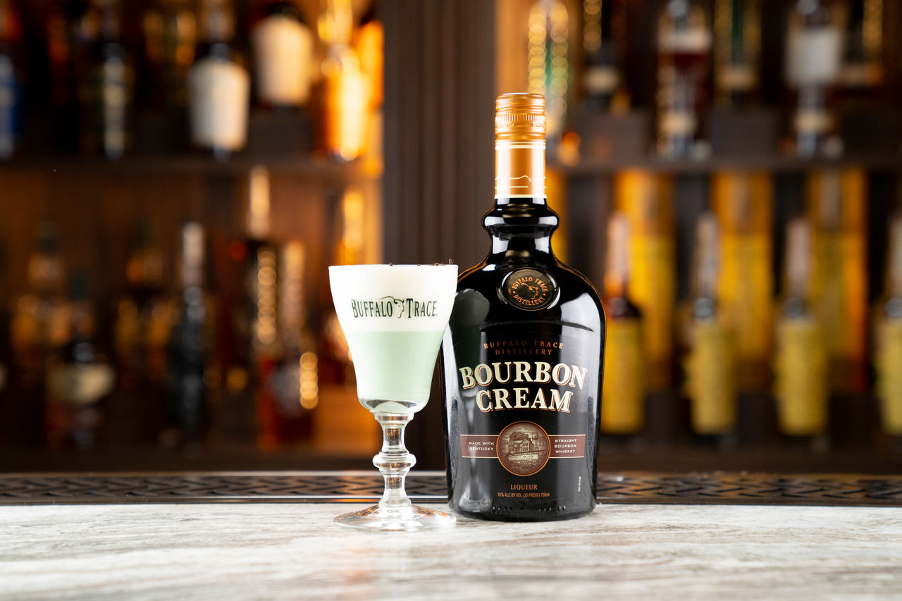 Bottle of Bourbon Cream on bartop with green buffalo drink
