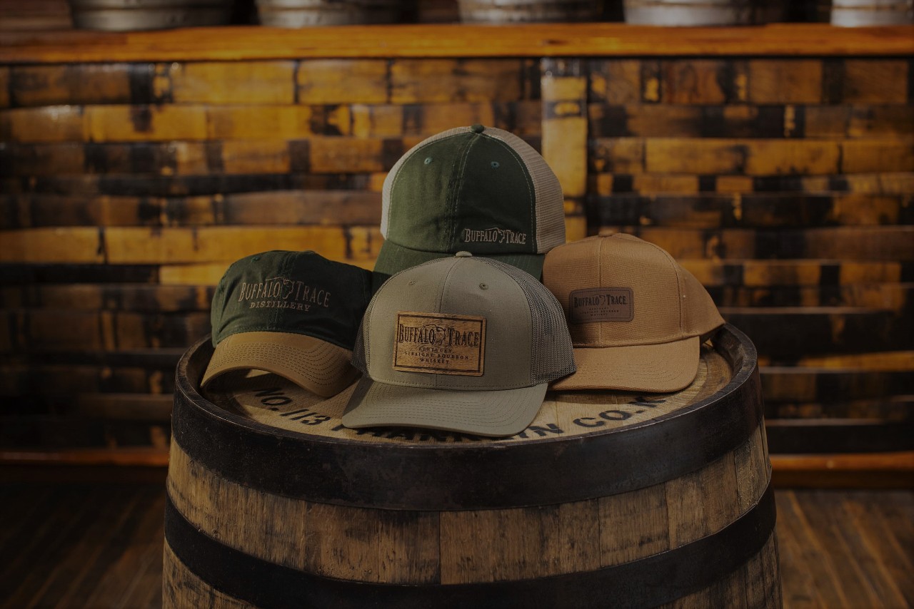 Assortment of Buffalo Trace Gift Shop ball caps displayed on a barrel